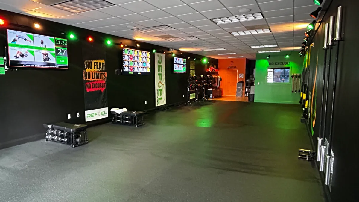 ReFuel Bootcamp studio floor with workout screens and equipment